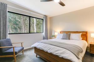 Un dormitorio con una gran ventana y una cama y una silla. en Karri Forest Vista-peaceful home with forest views, en Margaret River Town