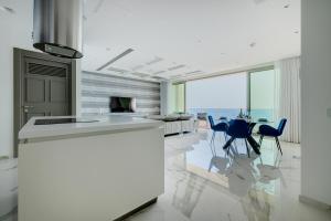 a kitchen with a counter and chairs and a table at Super Luxury Apartment in Tigne Point, Amazing Sea Views in Sliema