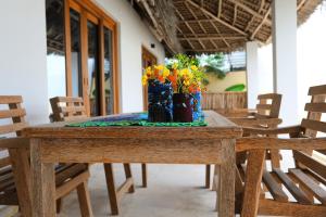 - une table en bois avec deux vases et des fleurs dans l'établissement Mkunguni Villas, à Bwejuu