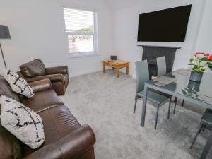 a living room with a couch and a table and a television at 10 Carmen Sylva Road in Llandudno