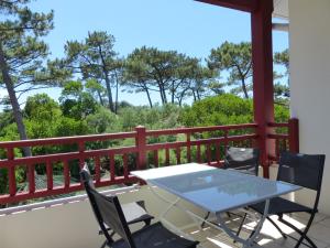 a table and chairs on a balcony with trees at Appartement Pour 4 Personnes- Residence L accalmie in Capbreton