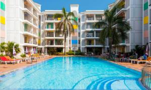 a large swimming pool with palm trees and buildings at Palmarinha de Goa in Calangute