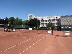 a tennis court with a net and a building at Négy Évszak Panziò in Siófok