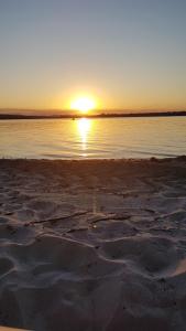 a sunset on a beach with the sun setting over the water at Couran Cove Resort Private Apartments, South Stradbroke Island, Gold Coast in South Stradbroke