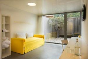 - un salon avec un canapé jaune et une table dans l'établissement Chromotel self check-in, à Mezzovico