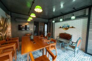 a dining room with a table and chairs and a couch at Lynlan Hostel & Cafe in Hat Yai