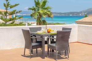 a table and chairs on a patio with a view of the ocean at Violeta de Mar in Playa de Muro