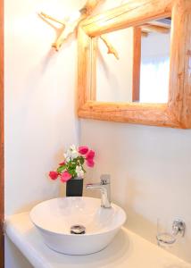 a bathroom sink with a mirror and a vase of flowers at Bonzoe #2 in Parikia