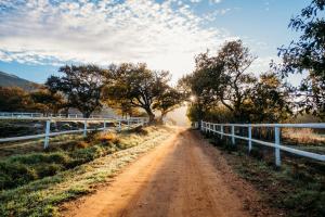 a dirt road with a fence on the side at White Water Farm in Stanford