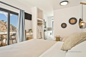 a white bedroom with a bed and a kitchen at Agnantema luxury suites in Karpathos