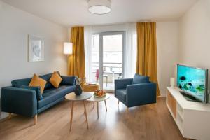 a living room with a blue couch and two chairs at DOMITYS Les Mosaïques in Rouen