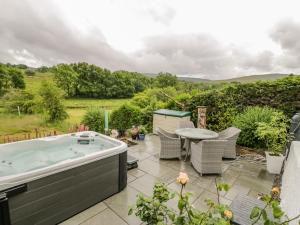 a hot tub on a patio with a table and chairs at White Roses Retreat in Betws-y-coed