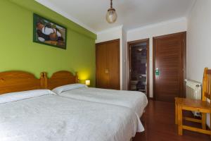1 dormitorio con cama blanca y pared verde en Hostal Chelsea, en Cedeira