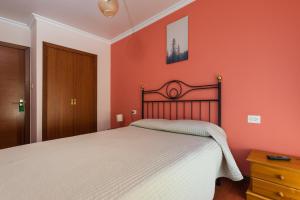 ein Schlafzimmer mit einem Bett mit einer orangefarbenen Wand in der Unterkunft Hostal Chelsea in Cedeira