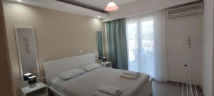 a white bedroom with a bed and a window at Meraki Skopelos in Skopelos Town