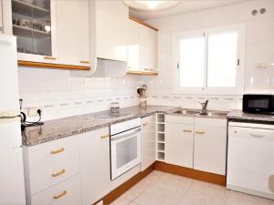 una cocina blanca con armarios blancos y fregadero en Villa Service - Barco 3º, en Calafell