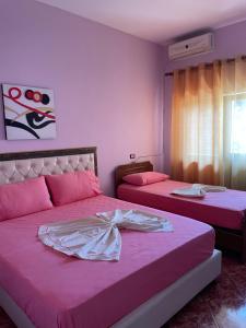 una camera con due letti con lenzuola rosa di Aragosta Shengjin 2 a Shëngjin