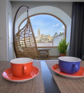 duas chávenas e pratos numa mesa com um baloiço em The View Matera em Matera