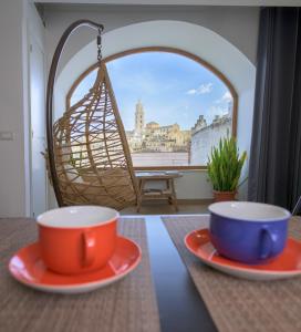 two cups and plates on a table with a swing at The View Matera in Matera +51 photos