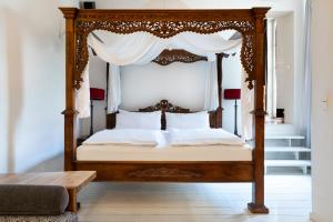a canopy bed with a wooden frame in a bedroom at Numa Berlin Belfort in Berlin