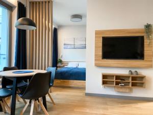 Habitación con mesa, TV y cama. en Sea Apartament - Plac Unii, en Gdynia