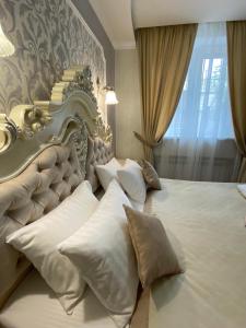 a bedroom with a large white bed with pillows at Grand Christer Hotel in Kyiv