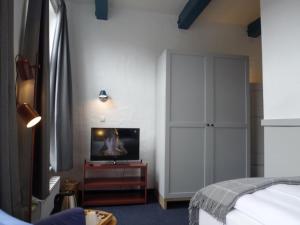 een slaapkamer met een bed en een tv op een tafel bij Hohes Haus in Greetsiel