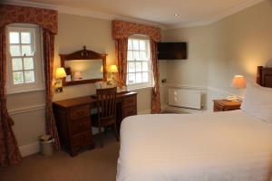 a hotel room with a bed and a desk and window at Rose in Vale Country House Hotel in St. Agnes