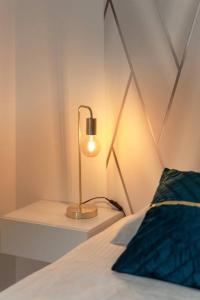 lampa siedząca na stole obok łóżka w obiekcie L'élégant portes de Paris- Parking-5'RER B w mieście Gentilly
