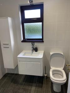 een badkamer met een toilet, een wastafel en een raam bij Minnie's Cottage in Stranocum