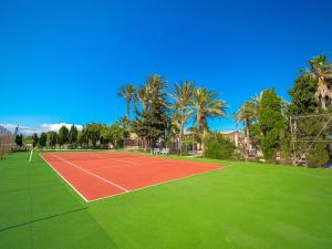 a tennis court with green grass and palm trees at Can Cap de Bou by Alquilair in Pollença