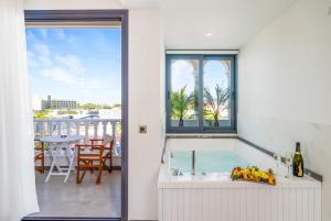 baño con bañera y balcón con mesa. en Drossia Residenza Boutique Hotel Malia en Mália