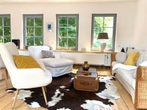 una sala de estar con muebles y ventanas blancos. en Ferienwohnung Weingut Villa Huesgen am Mönchhof, en Traben-Trarbach