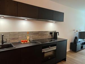 una cocina con armarios negros y una bandeja de fruta en la barra en Apartmenthaus Stade Schwingewiesen Apartment 1, en Stade