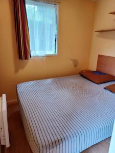 a bedroom with a large bed with a window at Charmant bungalow à Saint-Pierre-d'Oléron - Jardin privé in Saint-Pierre-dʼOléron