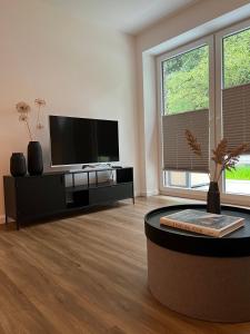 a living room with a flat screen tv and a coffee table at Apartmenthaus Stade Schwingewiesen Apartment 1 in Stade