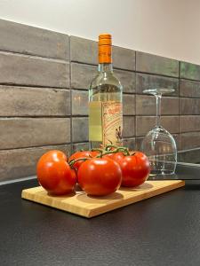 une bouteille de vin et quelques tomates sur un plateau de découpe dans l'établissement Apartmenthaus Stade Schwingewiesen Apartment 1, à Stade