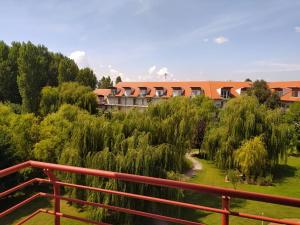a building with a red fence next to a garden at Cserke-Thermál Apartman in Cserkeszőlő