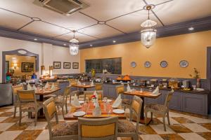 un restaurante con mesas y sillas en una habitación en The Manor Kashipur by Leisure Hotels, en Kāshīpur