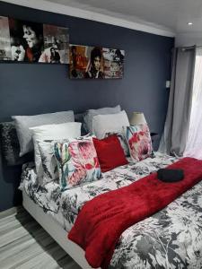 uma cama com um cobertor vermelho e almofadas em Ariah's Guesthouse and Self Catering em East London