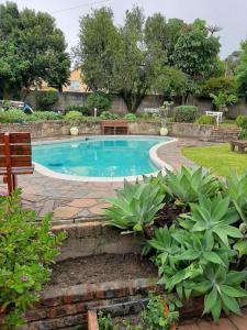 a swimming pool with a bench and some plants at Ariah's Guesthouse and Self Catering in East London