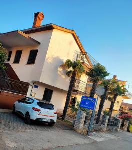 a car parked in front of a house with palm trees at Apartments Novigrad in Novigrad Istria