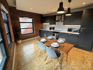 a kitchen with a wooden table and blue cabinets at Aire Apartments New York Styled Luxury Apartments in Leeds