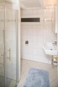 y baño blanco con lavabo y ducha. en Aarnhof-Wohnung-Schwalbe, en Archsum