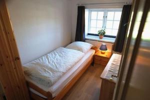 um pequeno quarto com uma cama e uma janela em Aarnhof-Wohnung-Schwalbe em Archsum