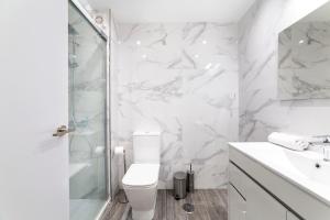 uma casa de banho branca com um chuveiro e um WC. em Apartamento Faro 2 em Roquetas de Mar