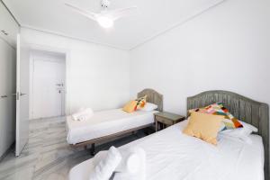 Duas camas num quarto com paredes brancas em Apartamento Faro 2 em Roquetas de Mar