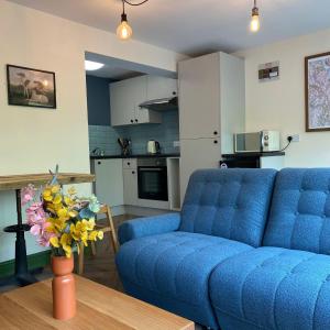- un salon avec un canapé bleu et une table dans l'établissement The Bolthole @ Bowness - Cosy 1 Bed Apartment, à Bowness-on-Windermere