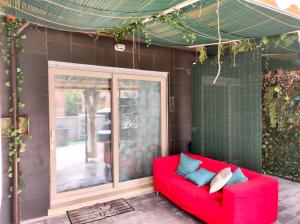 Tiny Green apartament in Rome - Magliana في روما: كنب احمر جالس امام المنزل