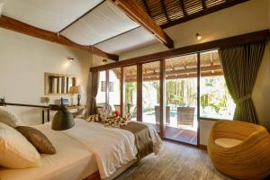 a bedroom with a large bed and a large window at Motu in Gili Trawangan